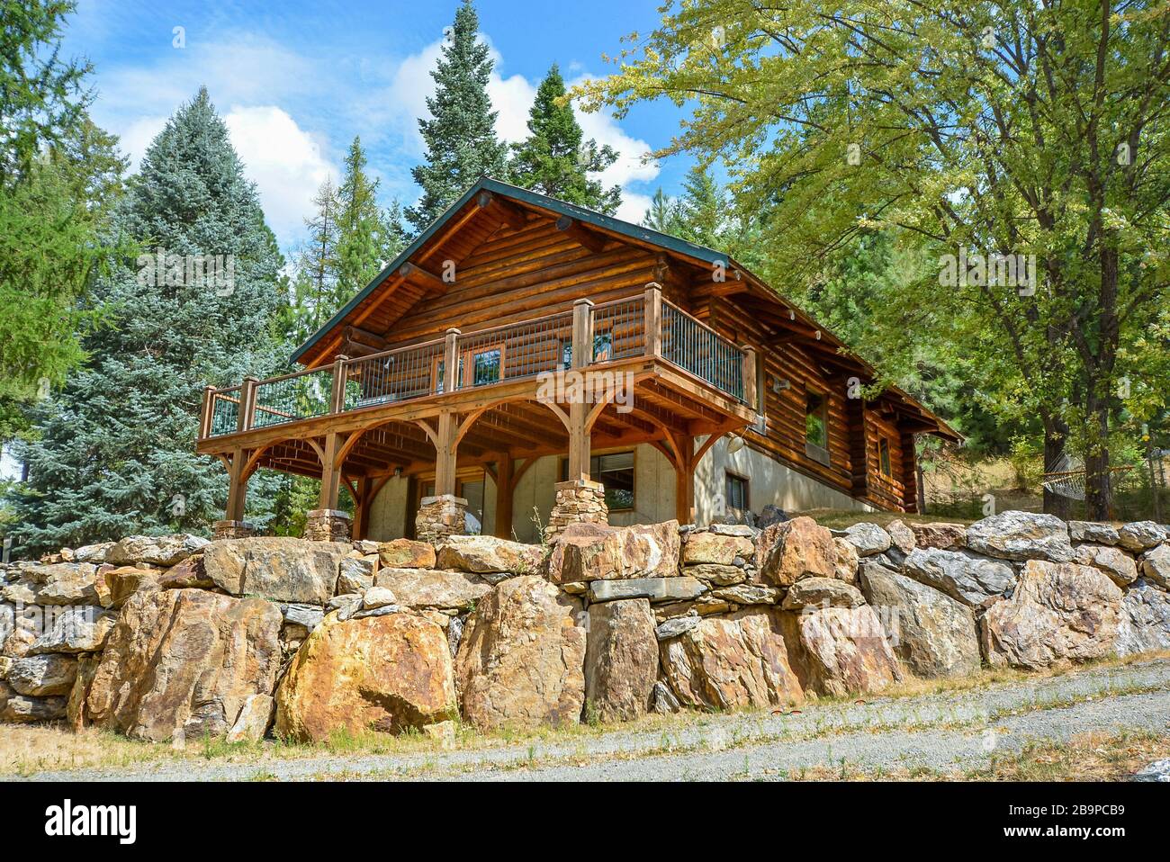 A picturesque rustic log home in the mountains surrounded by pine trees on a rocky hillside in Coeur d'Alene, Idaho. Stock Photo