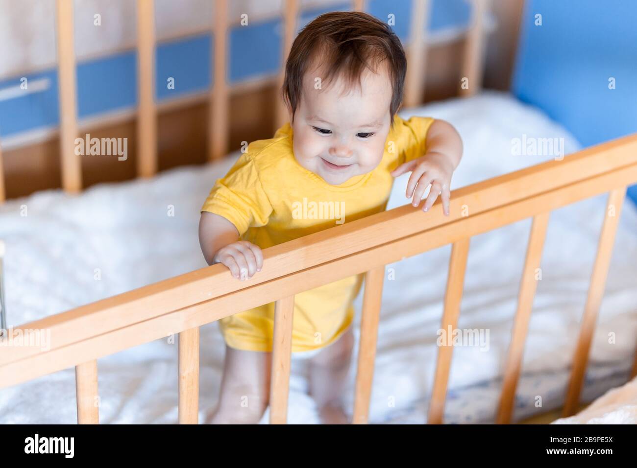 Happy baby girl with dark hair laughing and smiling in yellow t-shirt ...