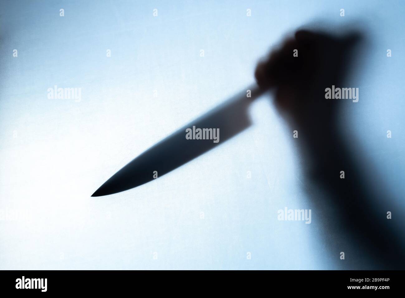 Blurred shadow of a hand holding a big and sharp knife Stock Photo