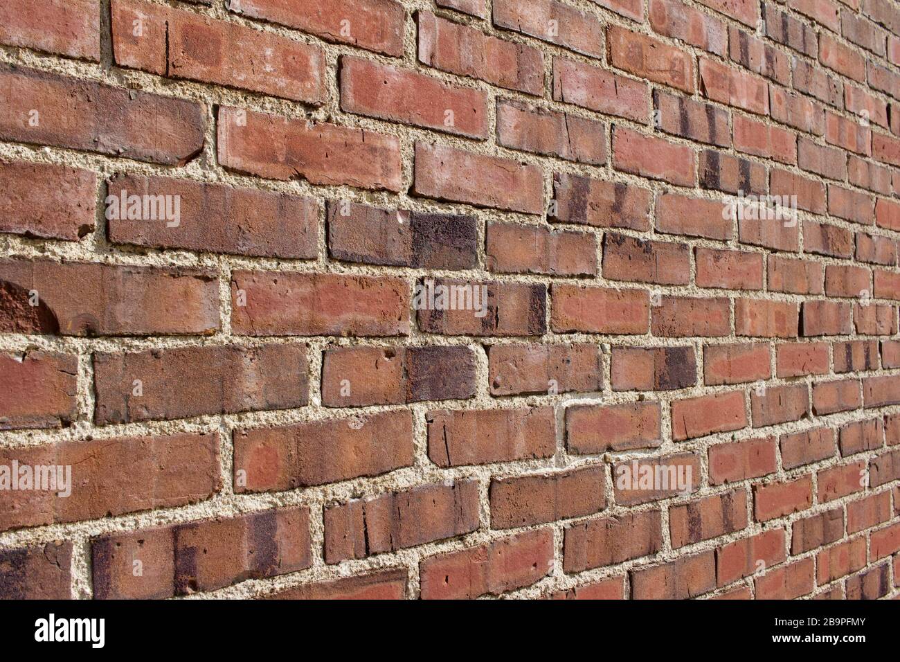 Older shabby chic red brick wall texture background with grungy mottled