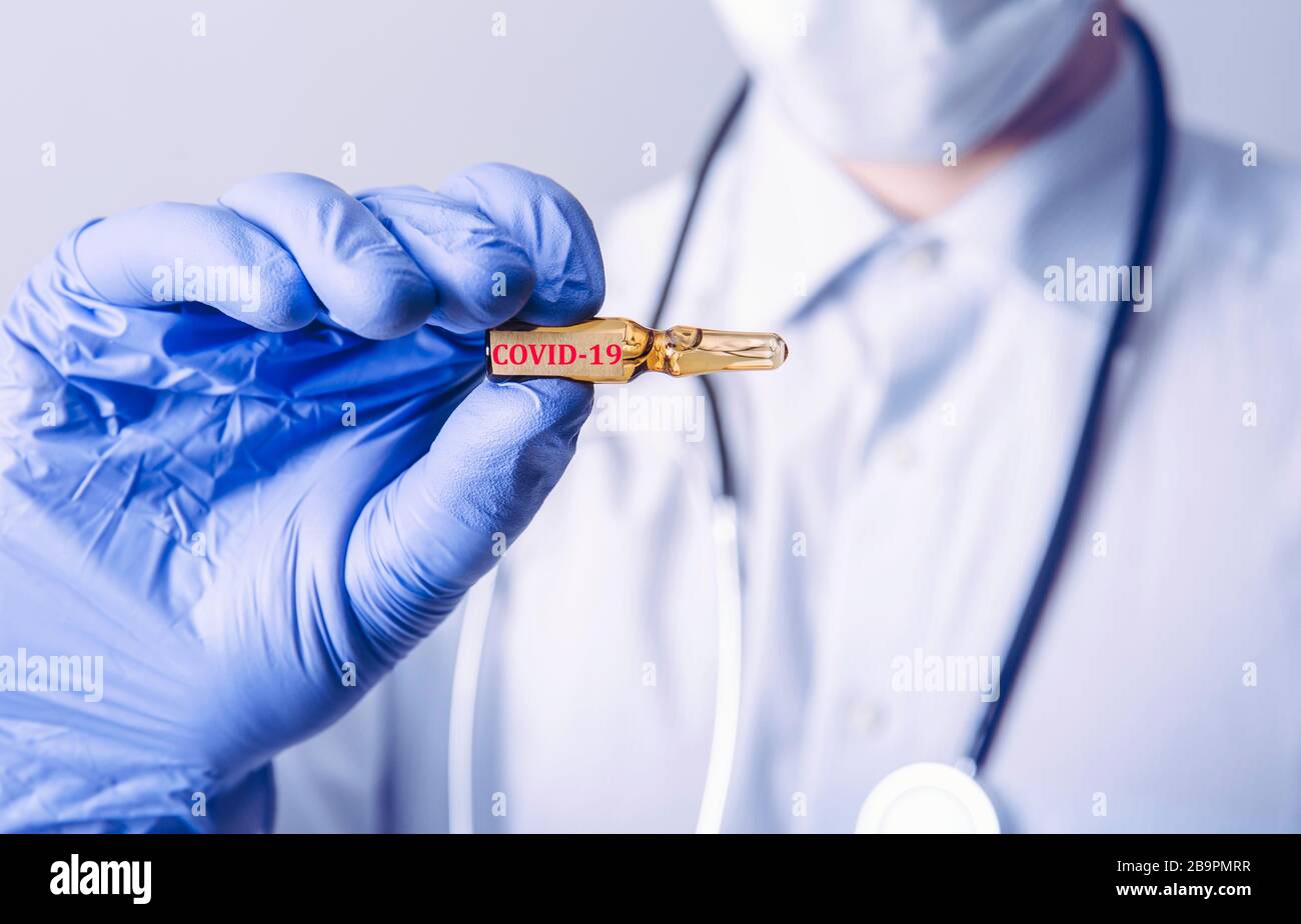 Conceptual image of medical doctor holding dose with COVID-19 vaccine cure. Stock Photo