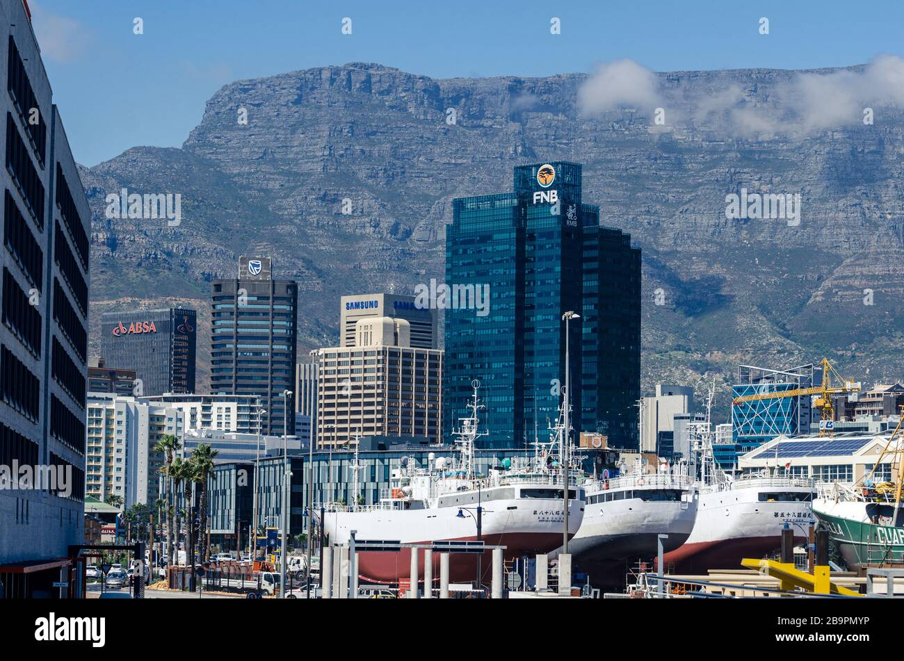 3 large Asian ships in dry dock in Alfred basin repair dock yard Silo district with city and Table mountain backdrop port of Cape Town South Africa Stock Photo