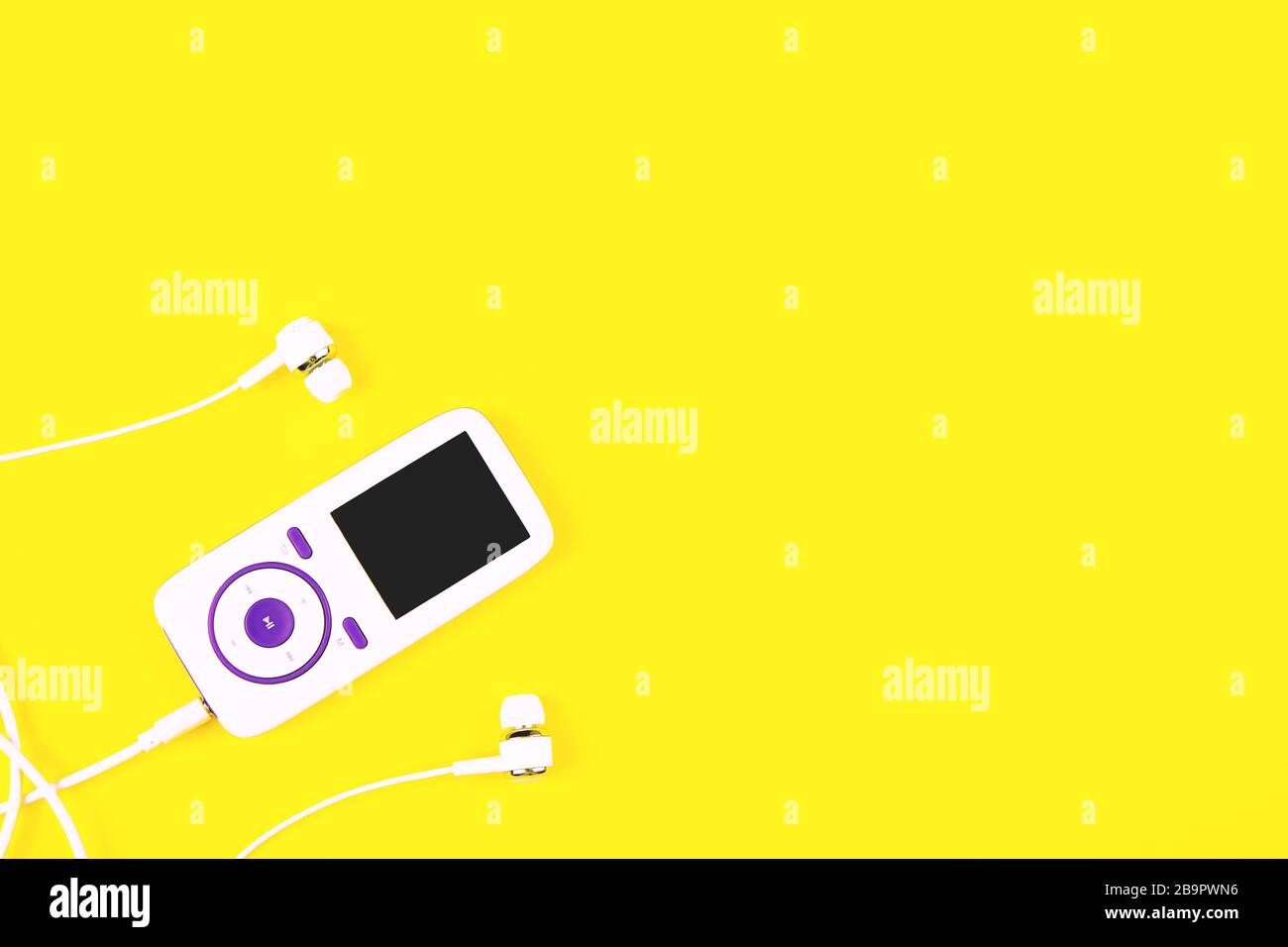 Close up image of white music player with earphones on yellow background. Place for text, flat lay. Stock Photo
