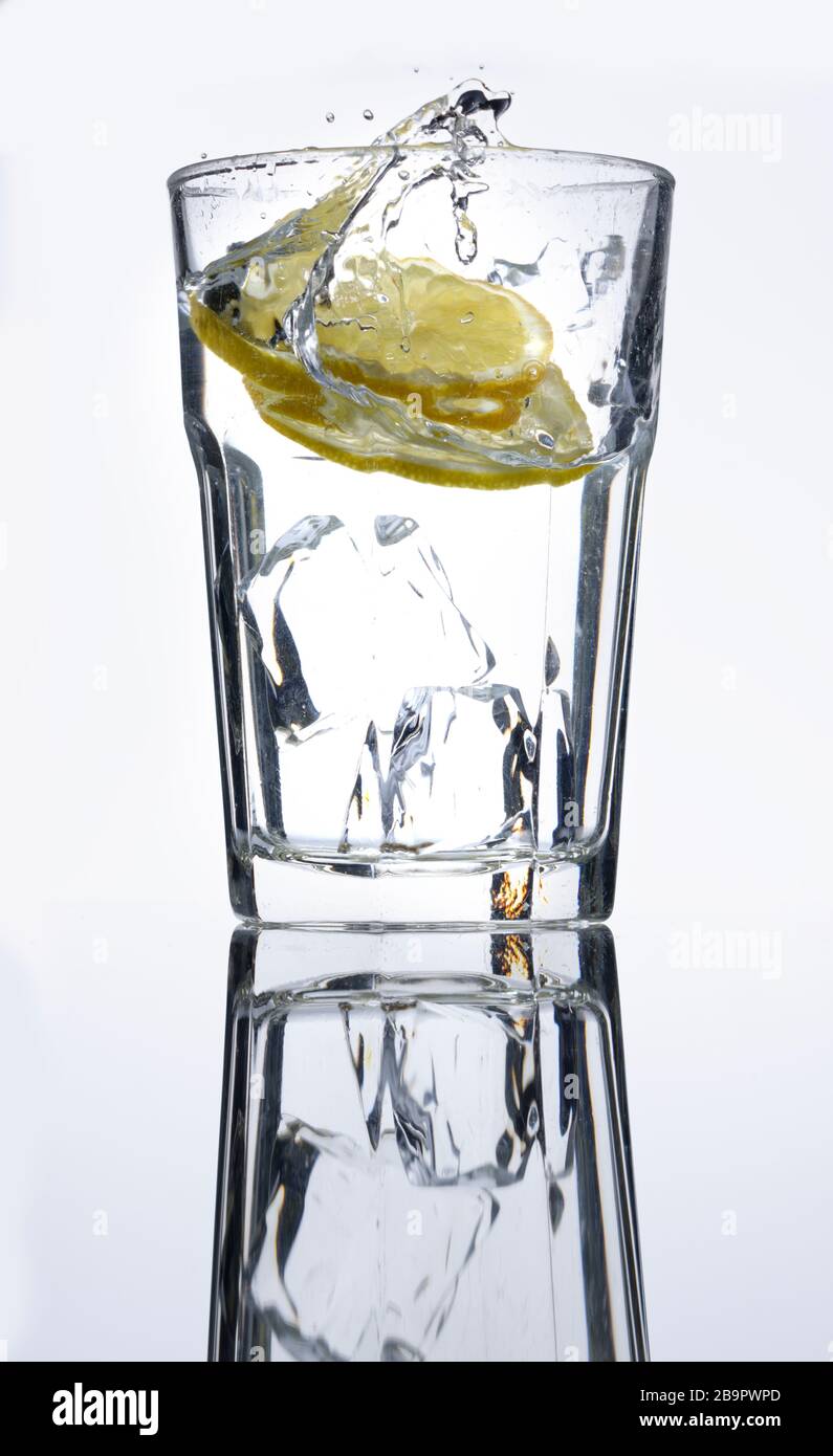 A French cafe glass with ice and water and a slice of lemon dropped into it. Stock Photo