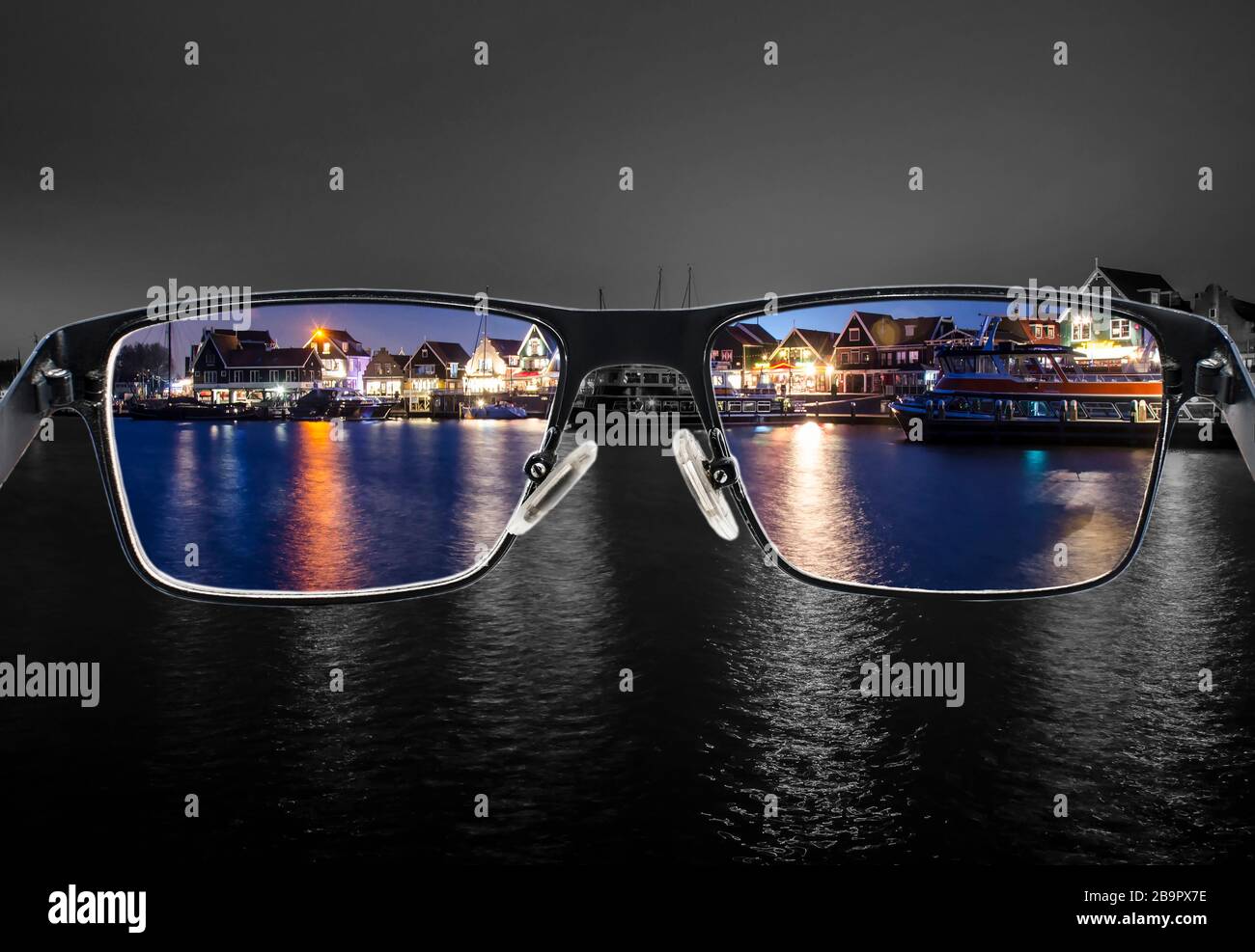 Black metal glasses looking through colorful night cityscape. Glasses for people with visual impairment. Color blindness. World perception. Stock Photo