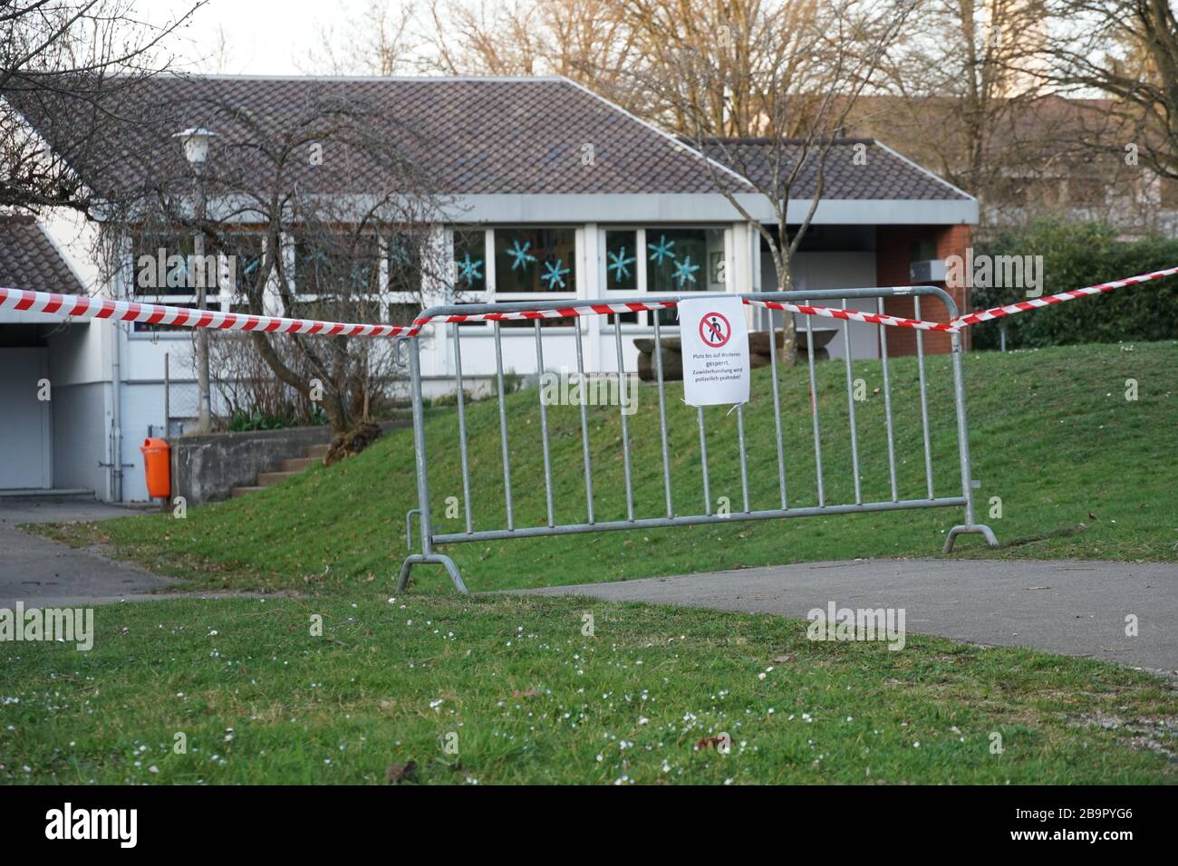 Closed nursery compound due to coronavirus in Urdorf, Switzerland.  A metal barrier and barrier tape with warning in German of no entry Stock Photo
