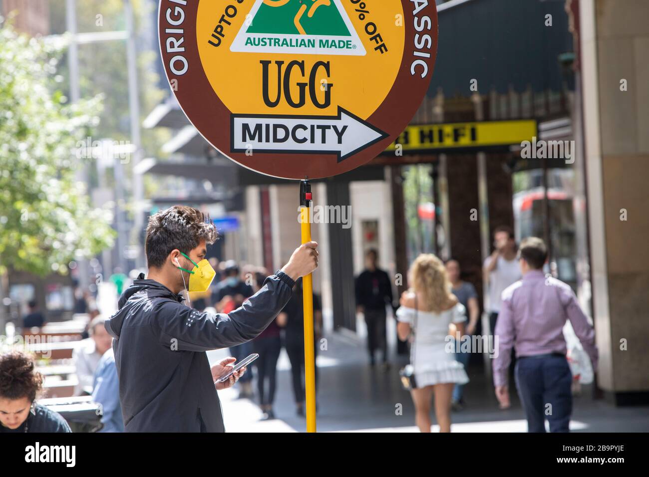 Sydney city centre, Australia. Wednesday 25th March 2020. Man with facemask  holding shop promotion sign for Ugg boots in Sydney city centre. Credit  Martin Berry/Alamy Live News Stock Photo - Alamy