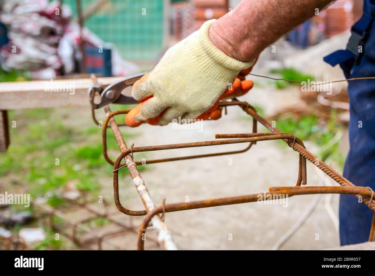Worker is tying rebar with wire using pliers, to make a reinforcing