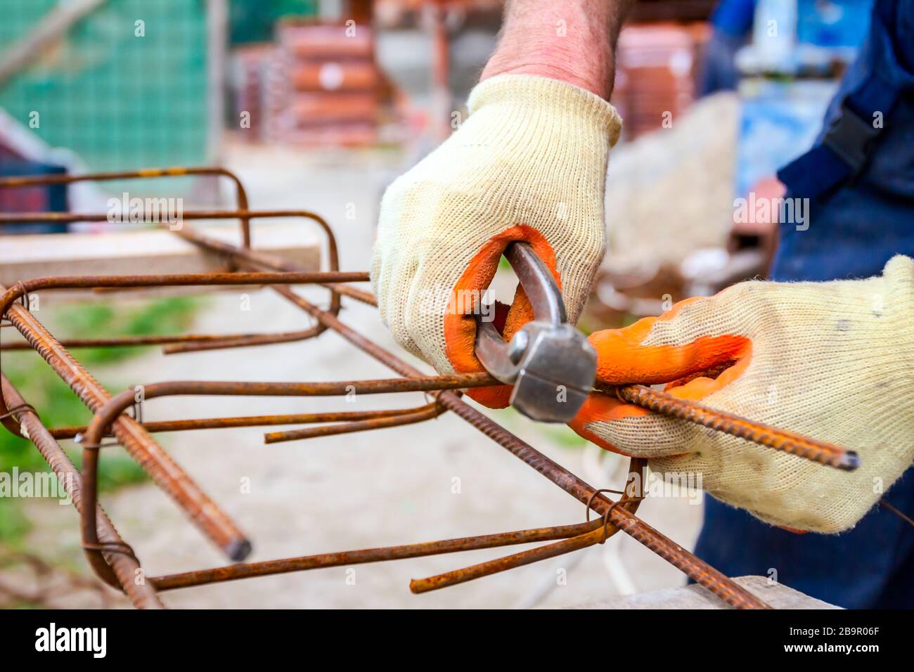 Worker is tying rebar with wire using pliers, to make a reinforcing frame for concrete beam