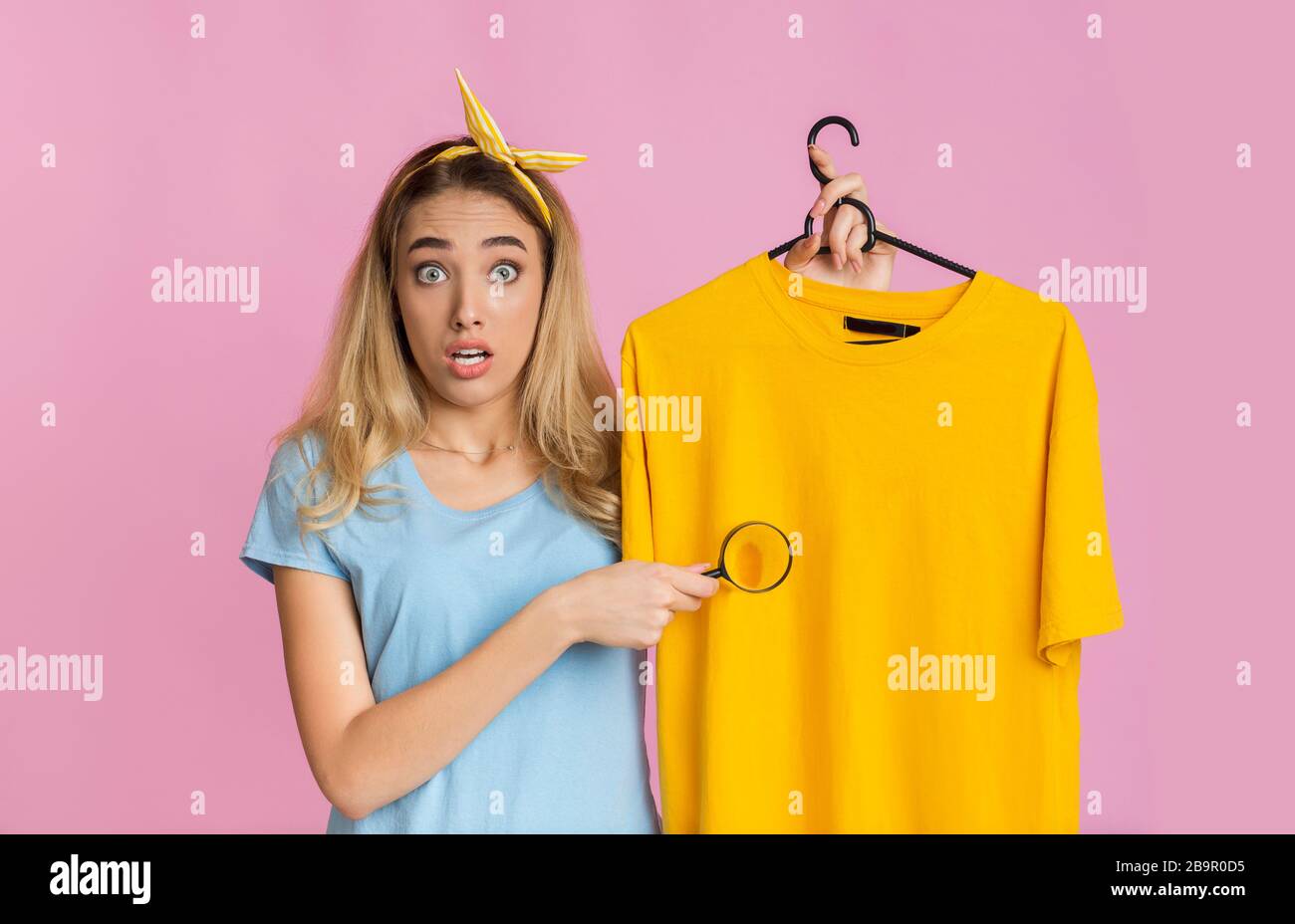 Removing stains from clothing concept. Housewife with magnifier Stock Photo