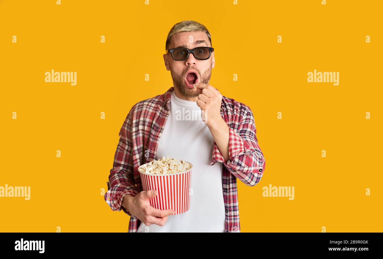 Surprised man in 3D glasses eating popcorn Stock Photo