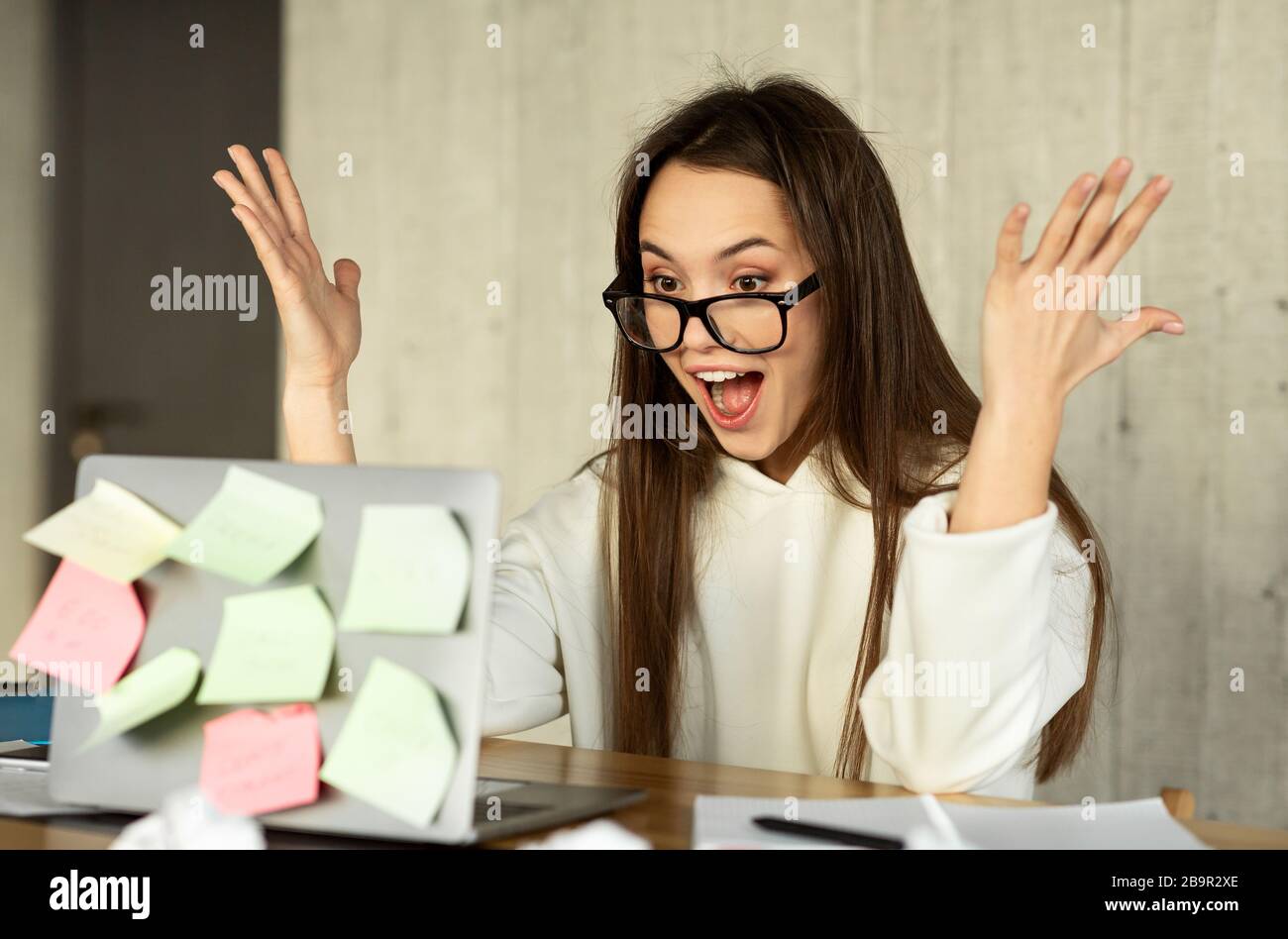 Excited young business woman keeping arms raised Stock Photo