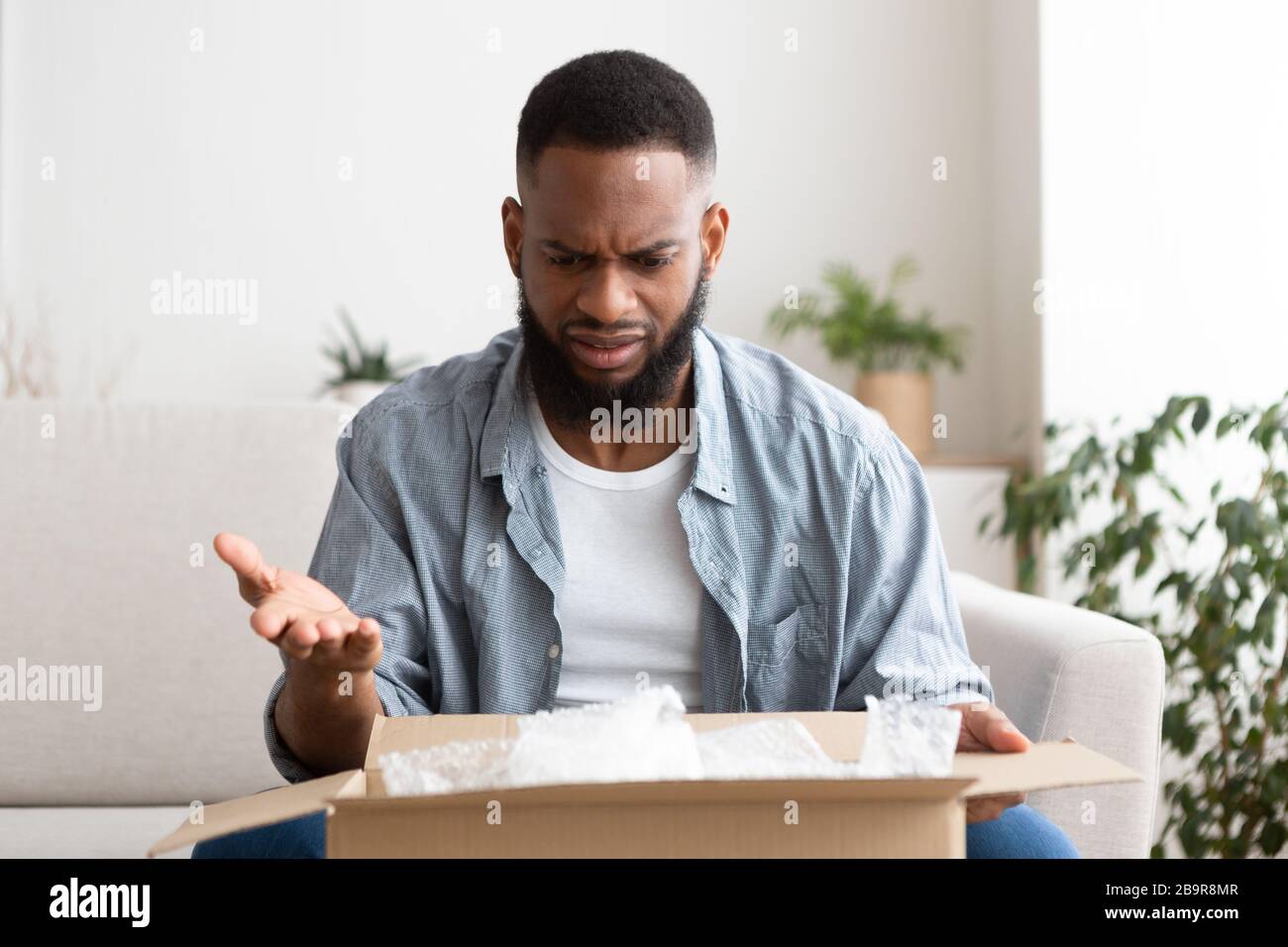 Purchase delivery error. Surprised man opened package Stock Photo