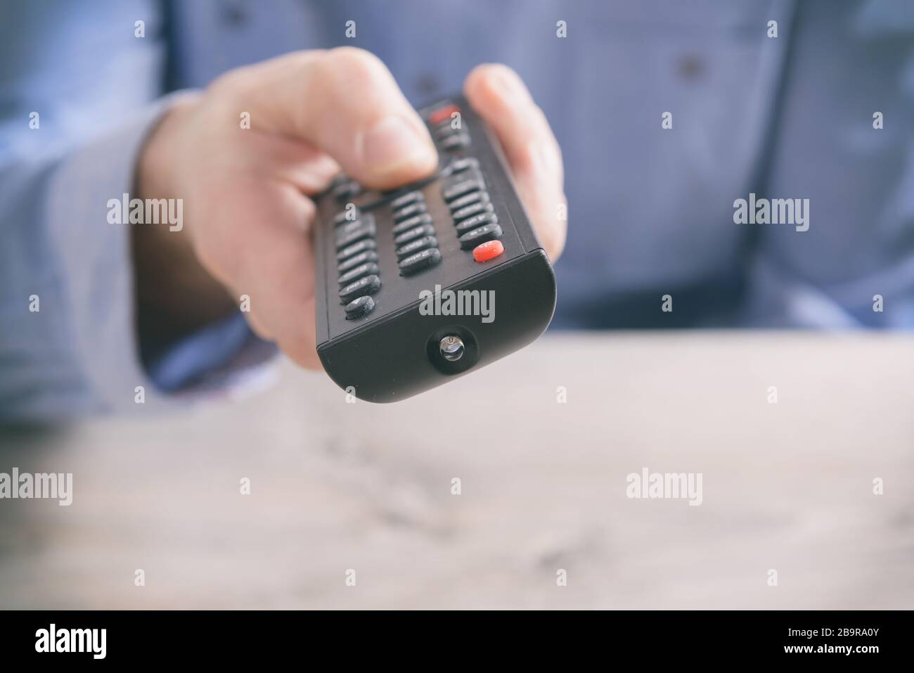Man holding tv remote control and changing TV channels Stock Photo