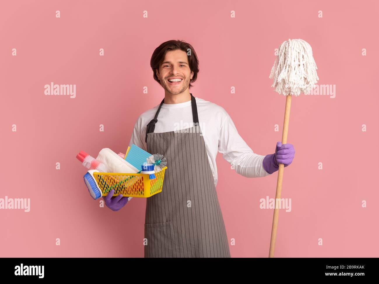Millennial Man Posing With Mop And Cleaning Supplies Over Pink Background Stock Photo