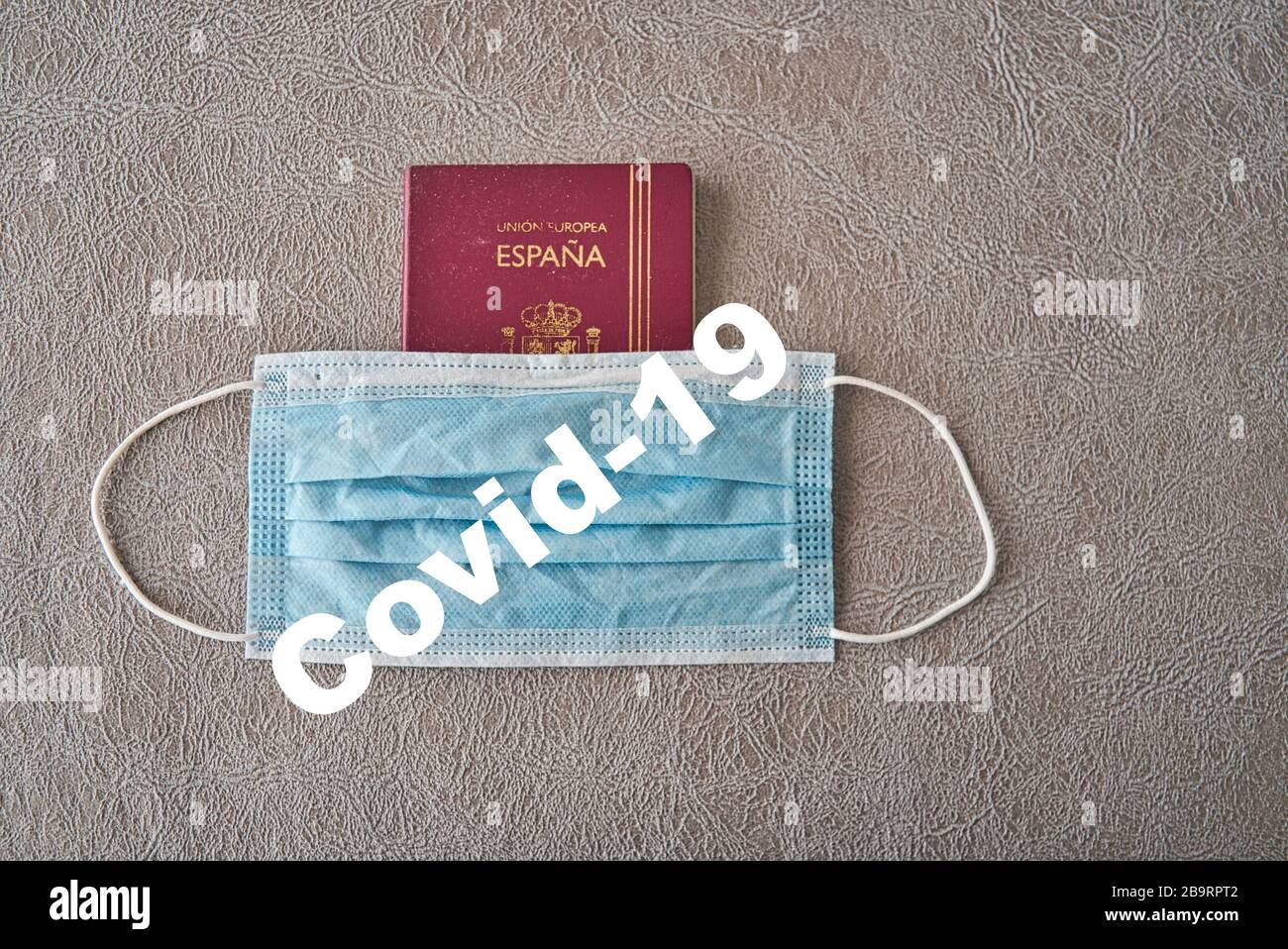 Spanish international passport protected with a cotton surgical mask as protection from the coronavirus pandemic, covid19. Symbology of the precarious Stock Photo