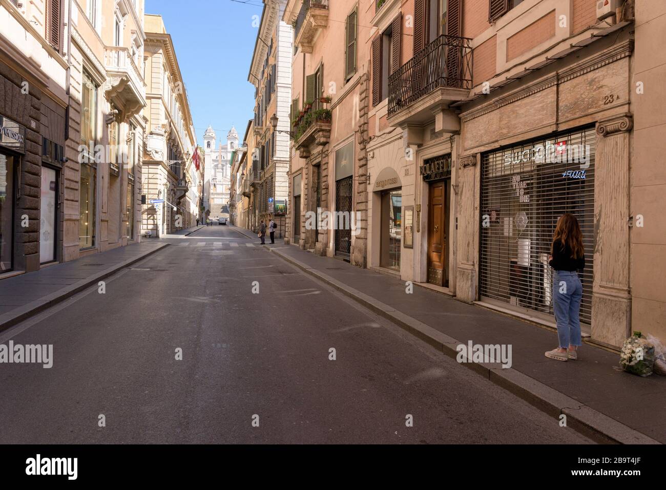 ROME, ITALY - 12 March 2020: A woman stands in front of closed shops in Via dei Condotti, next to the Spanish Steps, Rome, Italy. One must justify the Stock Photo