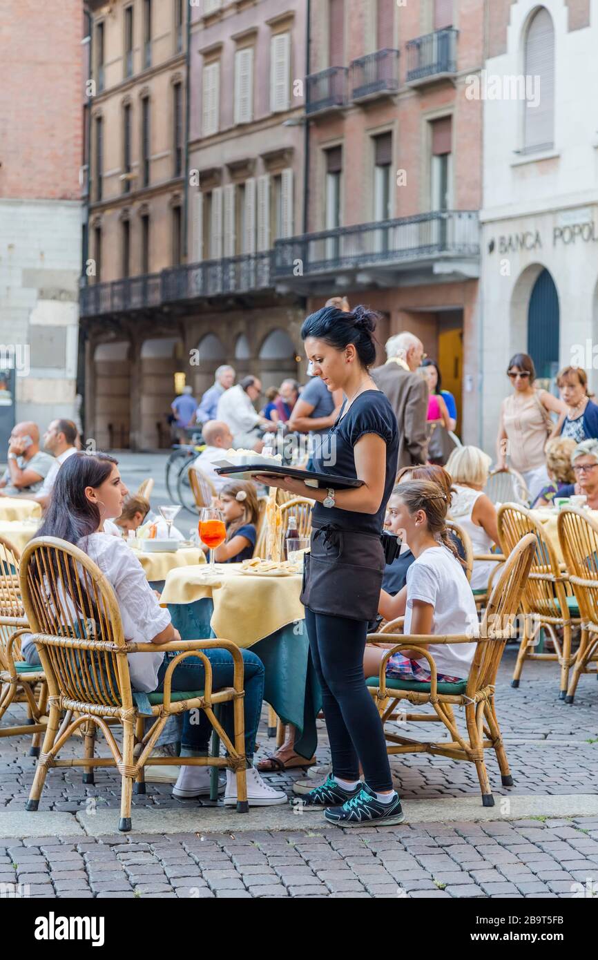 CREMONA, ITALY - SEPTEMBER 02, 2015: A waiter girl takes an order from visitors to a street cafe in Piazza del Comune in Cremona. Italy Stock Photo
