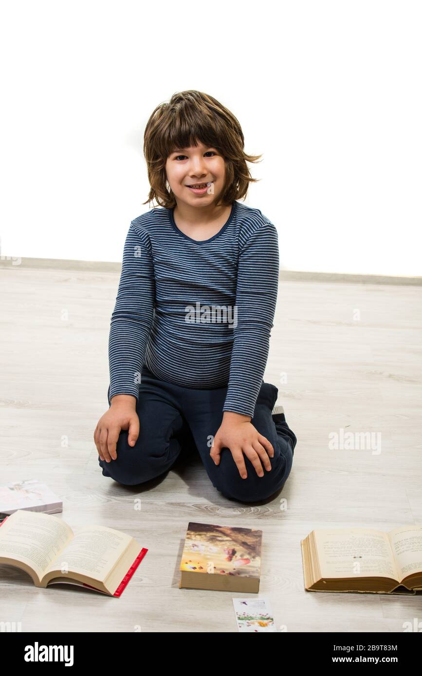 Boy sitting down on floor and reading books Stock Photo