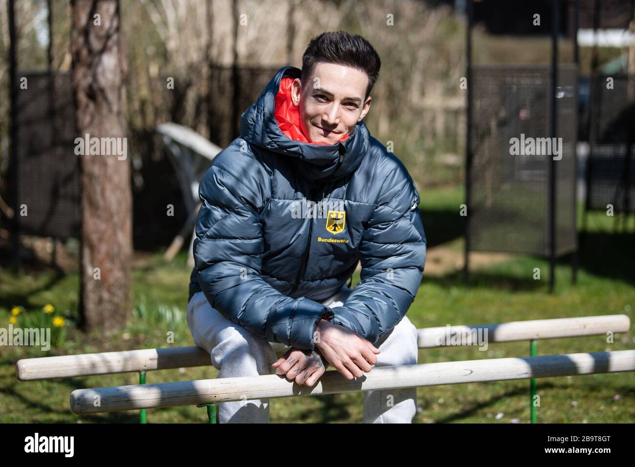 Unterhaching, 24th Mar, 2020. Marcel Nguyen, gymnast, is sitting on a training bar his mother's garden. Due the corona virus, training in the gym is currently only possible to