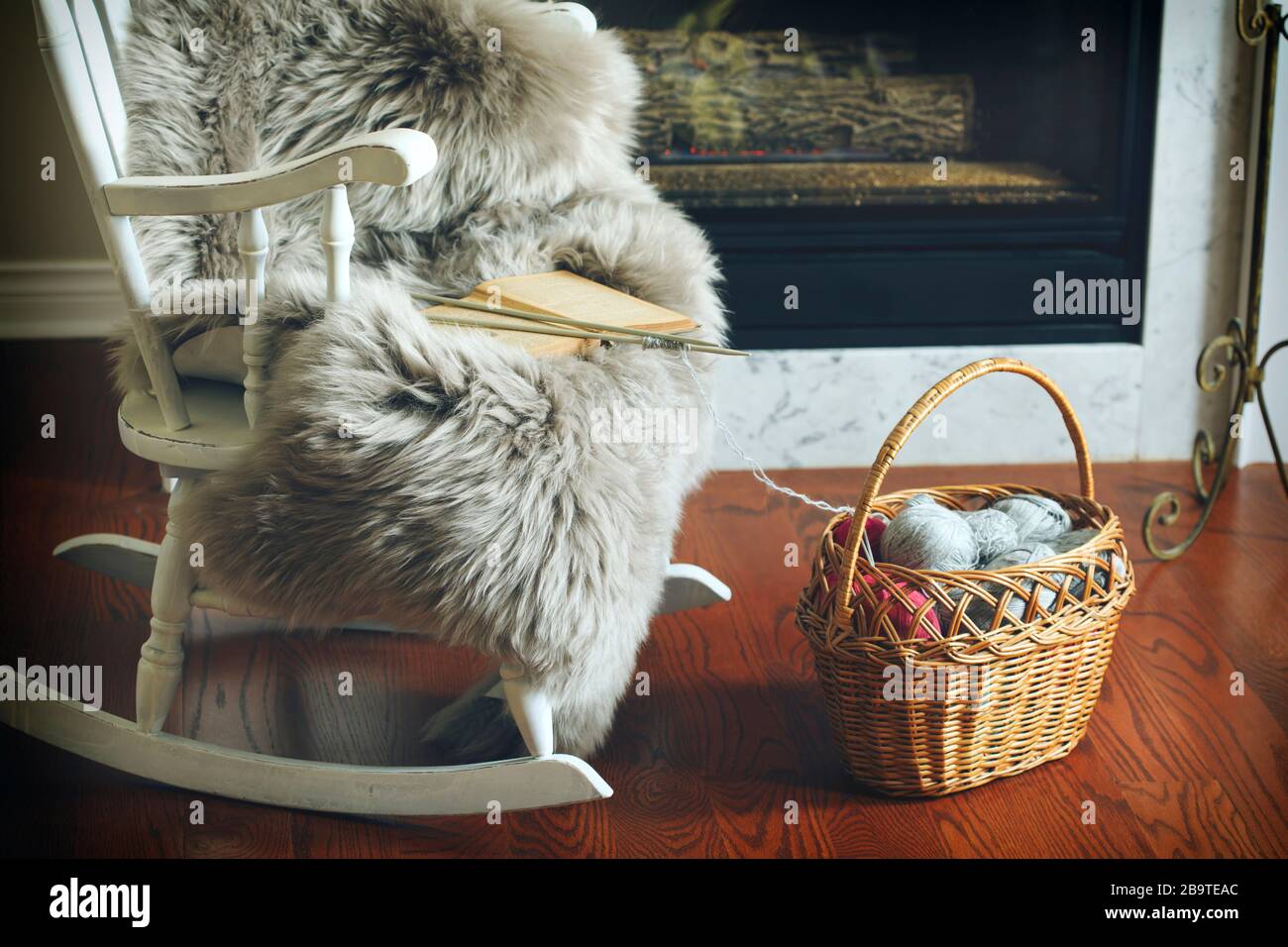Basket with balls of yarn near chair and fireplace Stock Photo - Alamy