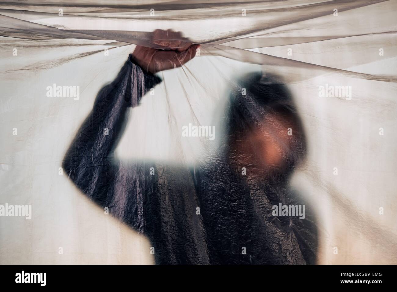 Drug addiction concept, blurred male person with hoodie behind plastic curtain, selective focus Stock Photo