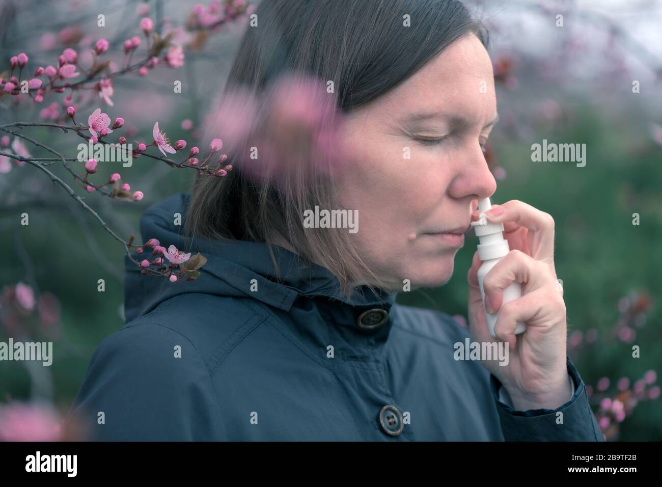 Woman using nasal spray outdoors for tree pollen allergy treatment