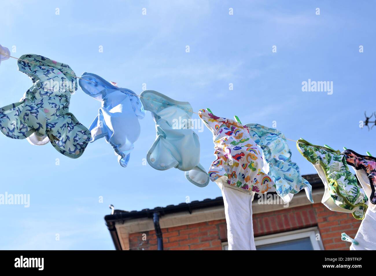 Southampton, U.K. , 24 Mar, 2020. A variety of different styles and themes of cloth nappies hanging out to dry on a washing line in sunny weather. Stock Photo
