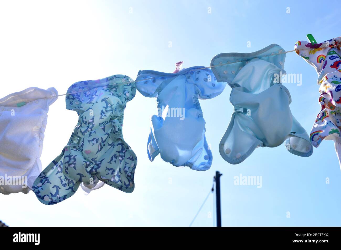 Southampton, U.K. , 24 Mar, 2020. A variety of different styles and themes of cloth nappies hanging out to dry on a washing line in sunny weather. Stock Photo