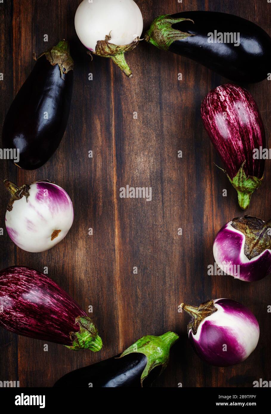 Fresh eggplants of different color and variety on a wooden background, copy spce Stock Photo