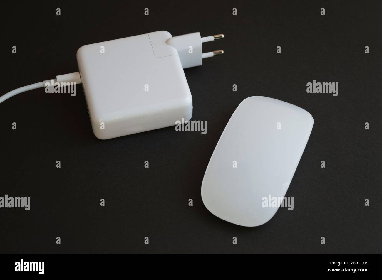 Minimalistic combination of white mouse and charger for laptop on the dark background Stock Photo