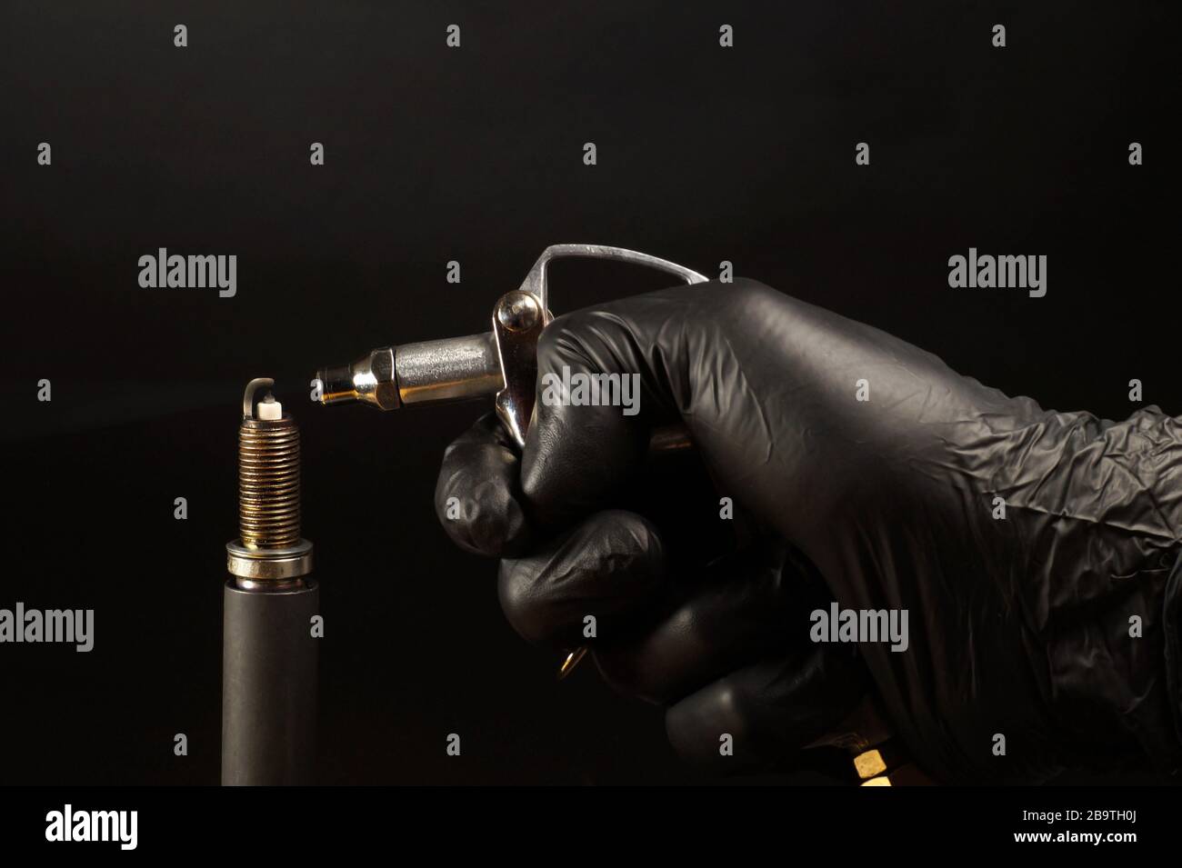 Internal combustion engine service. Cleaning the spark plug with compressed air. Stock Photo