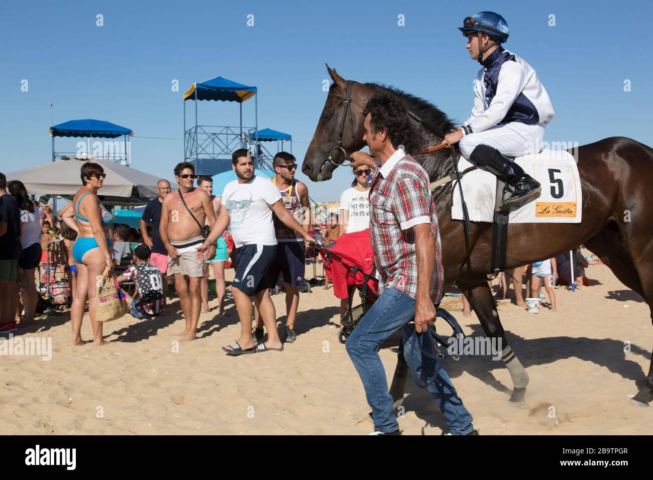 A mounted male jockey being led to the course during the annual August horserace meeting   on the beach at Sanlucar de Barrameda, Cadiz, Spain. 3rd Au Stock Photo