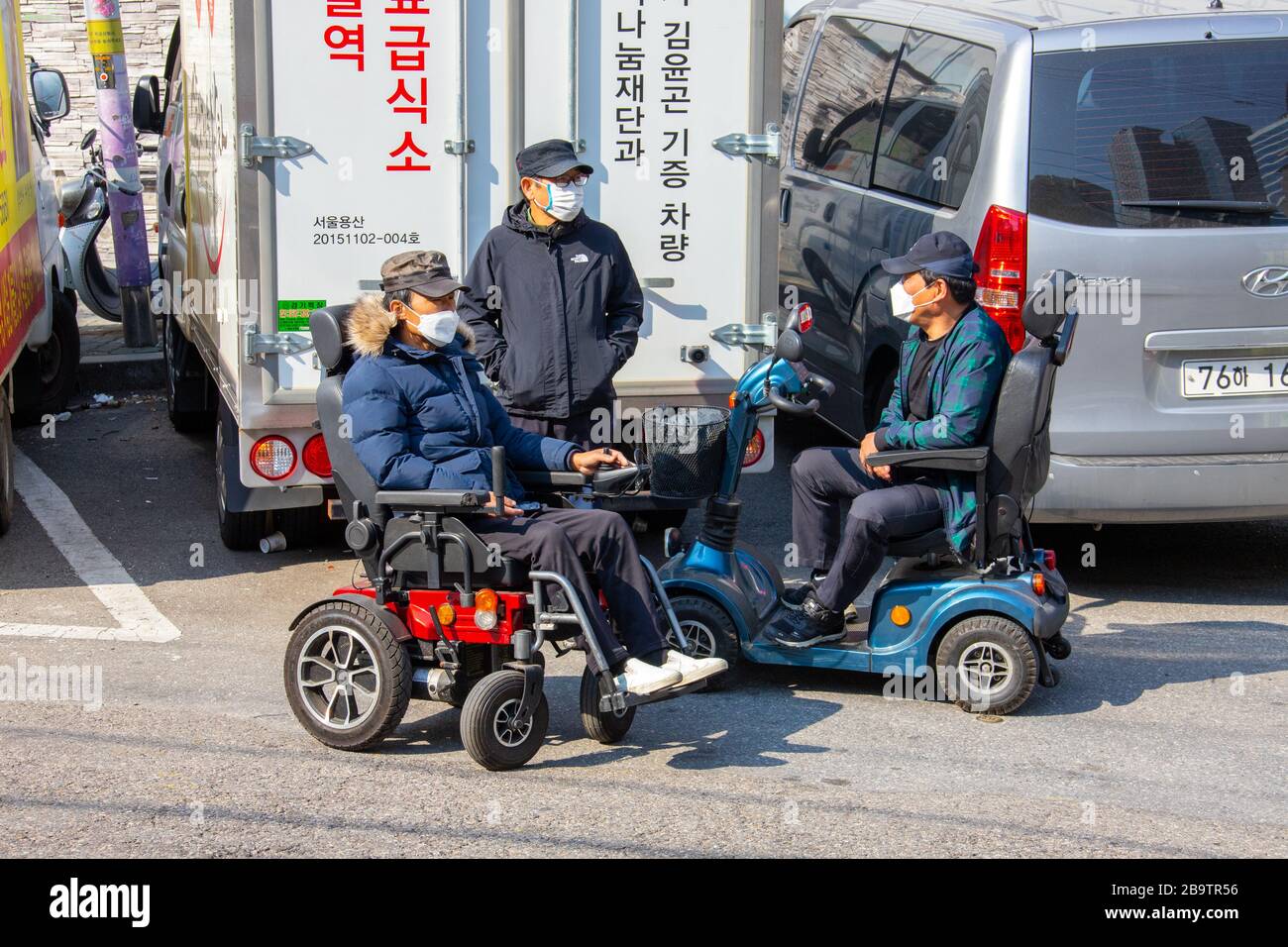 Men on mobility scooters wearing a masks during the Coronavirus pandemic, Seoul, South Korea Stock Photo
