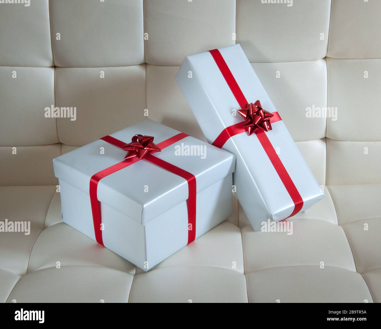 Two gift wrapped presents on white padded chair Stock Photo