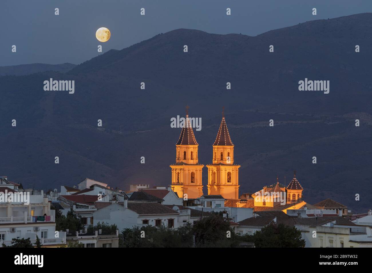 The rising moon in the final phase of a lunar eclipse, and the twin bell towers of the church in Órgiva, Granada, Andalusia, Spain. 7th August 2017. Stock Photo