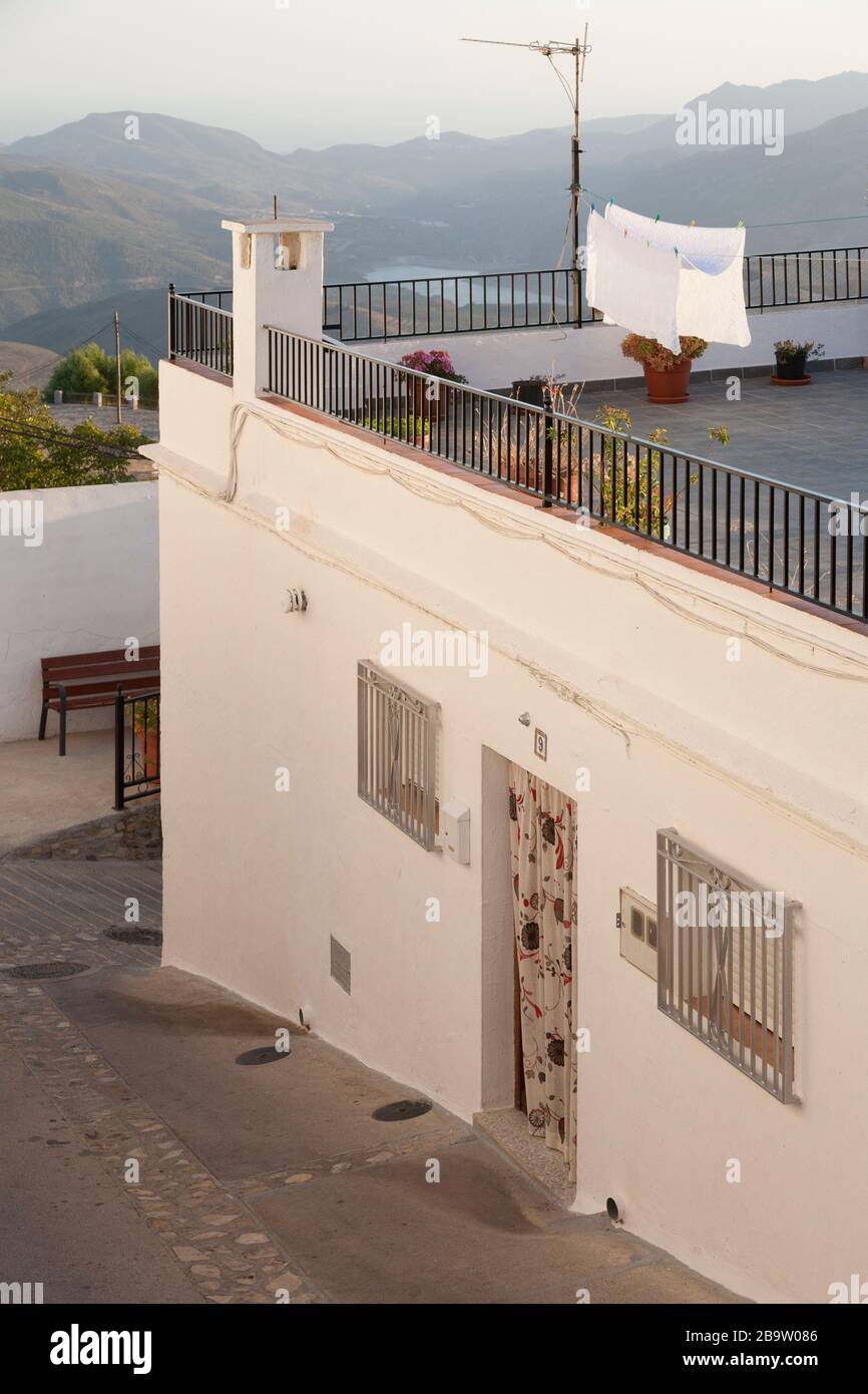 A house with laundry drying on a washing line on the roof terrace, and views beyond to Rules reservoir, Cañar, Granada, Spain Stock Photo