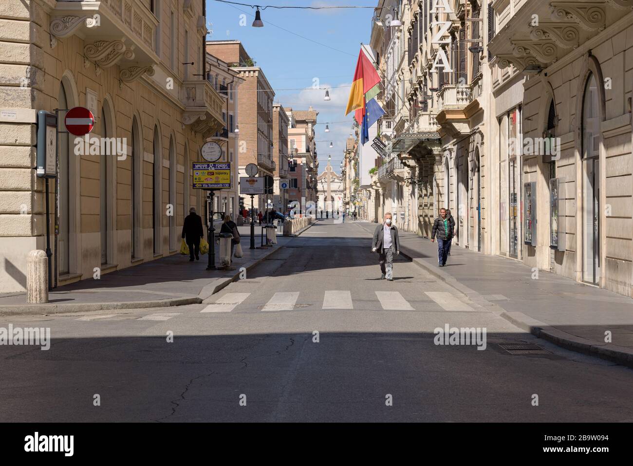 ROME, ITALY - 12 March 2020: A man with a face mask walks down Via del Corso amongst few passersby, Rome, Italy, following the nationwide coronavirus Stock Photo