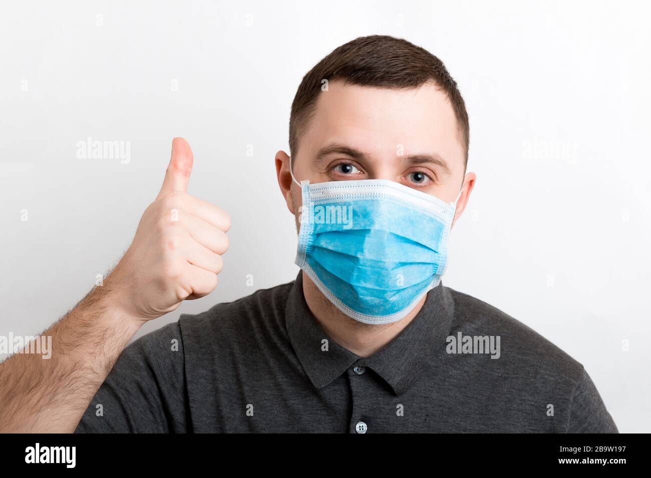 Portrait of young man wearing a medical mask at white background ...
