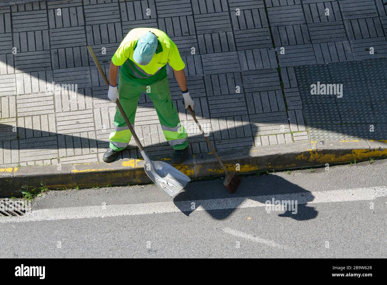 Street sweeper with broom and shovel working on city. Public cleaning concept Stock Photo