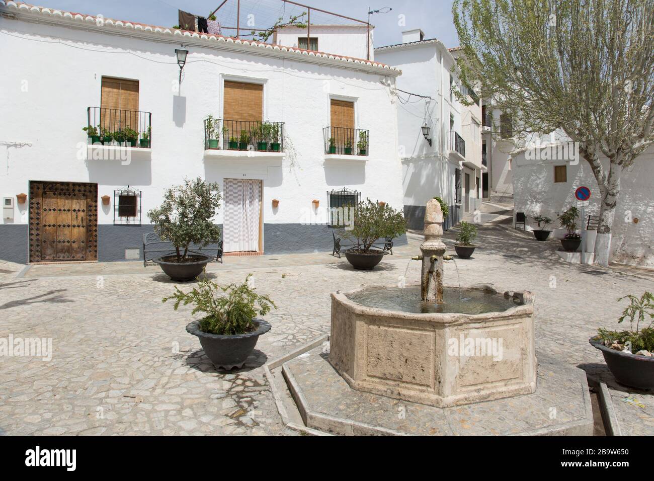 Houses and a stone fountain in Plaza Santa Ana, Cañar, Granada, Andalusia, Spain Stock Photo