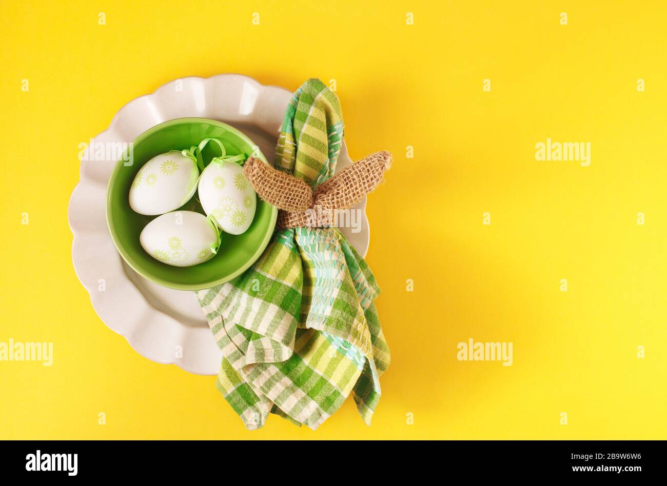 Happy Easter table setting with Easter decoration eggs on yellow background, top view, flat lay, copy space Stock Photo