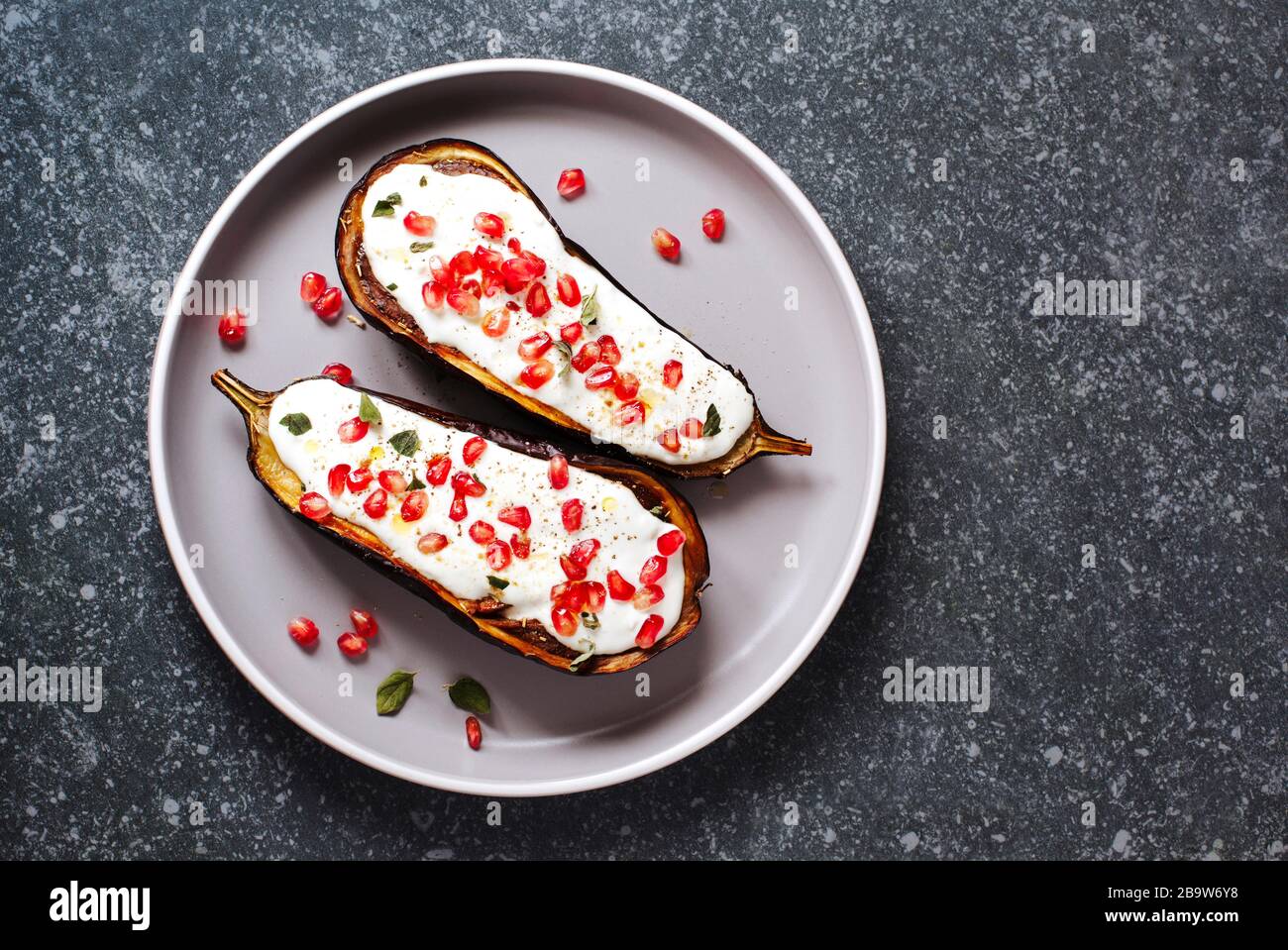 Baked eggplants with garlic yogurt sauce and pomegranate, top view