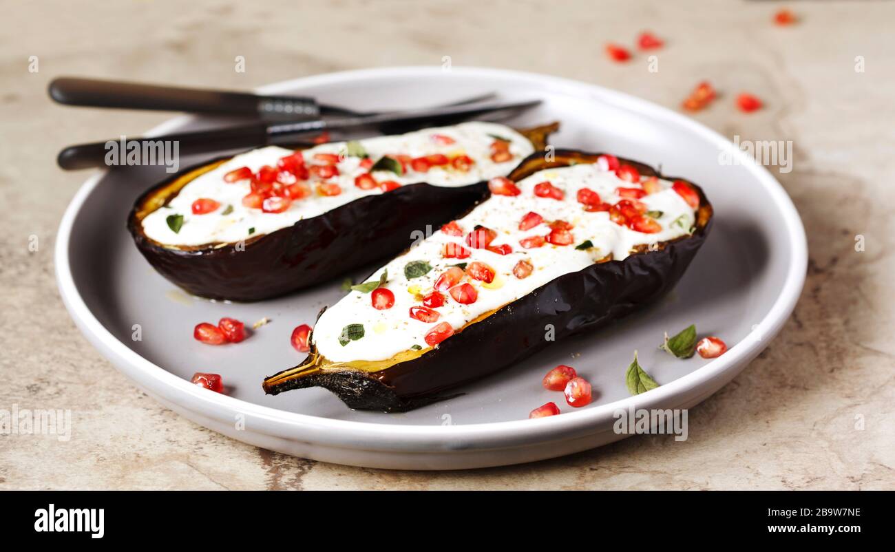 Baked eggplants with garlic yogurt sauce and pomegranate Stock Photo