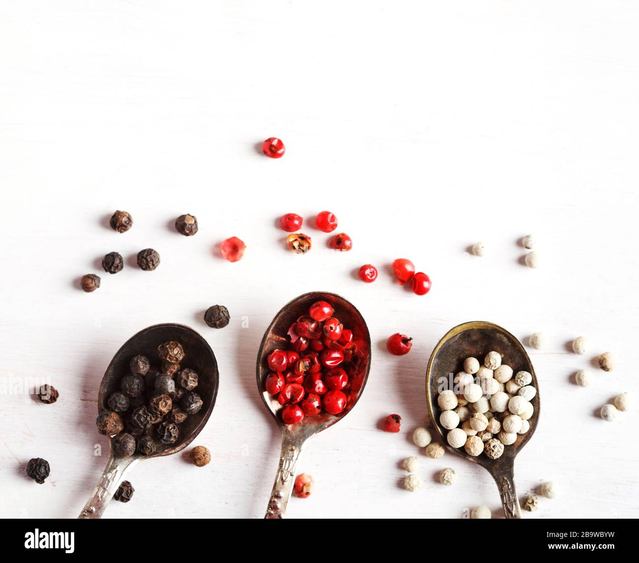 Pink, White and black peppers in spoons, top view, copy space Stock Photo