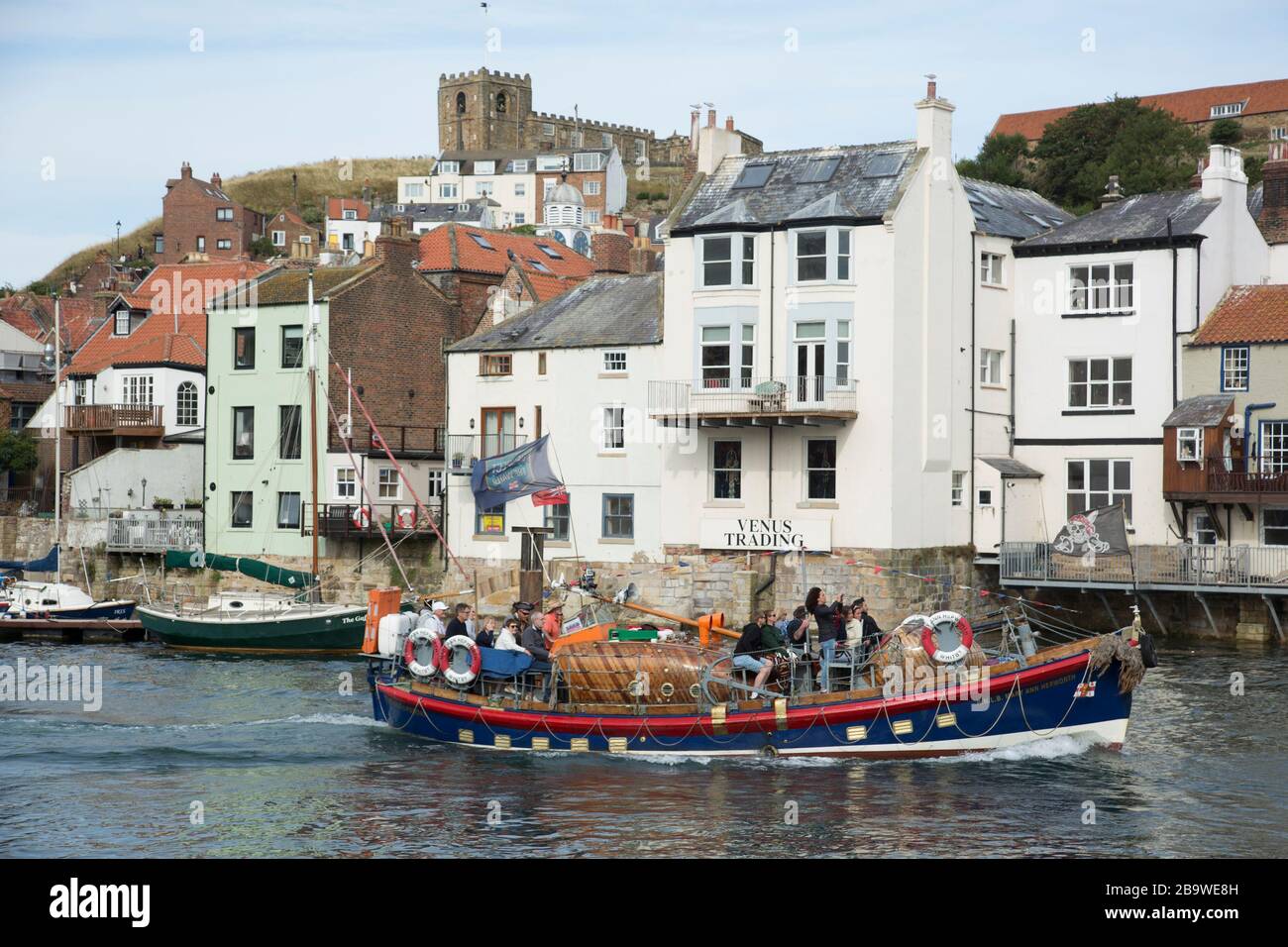 The Old Lifeboat with tourists aboard moves through the harbour during the annual summer regatta in Whitby, North Yorkshire, England, United Kingdom Stock Photo