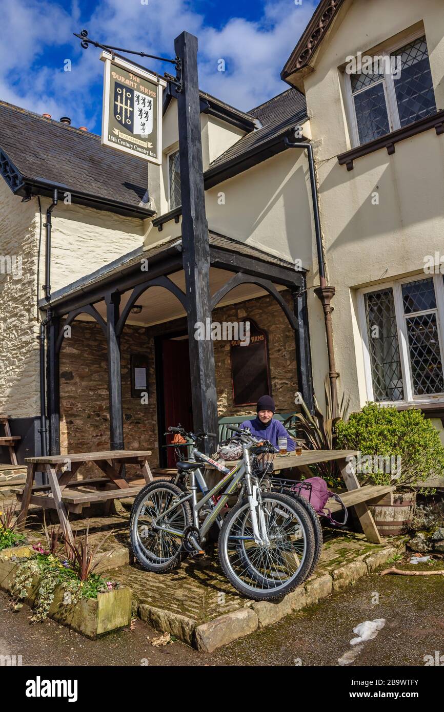 A cyclist resting and taking a break outside the Durant Arms Pub in Ashsprington in the Dart Valley, South Hams, Devon, UK. March 2018. Stock Photo