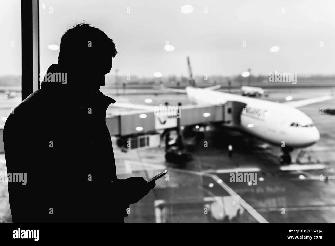 Silhouette of a man at the airport. Man waiting for his flight. Black and white photo. Stock Photo