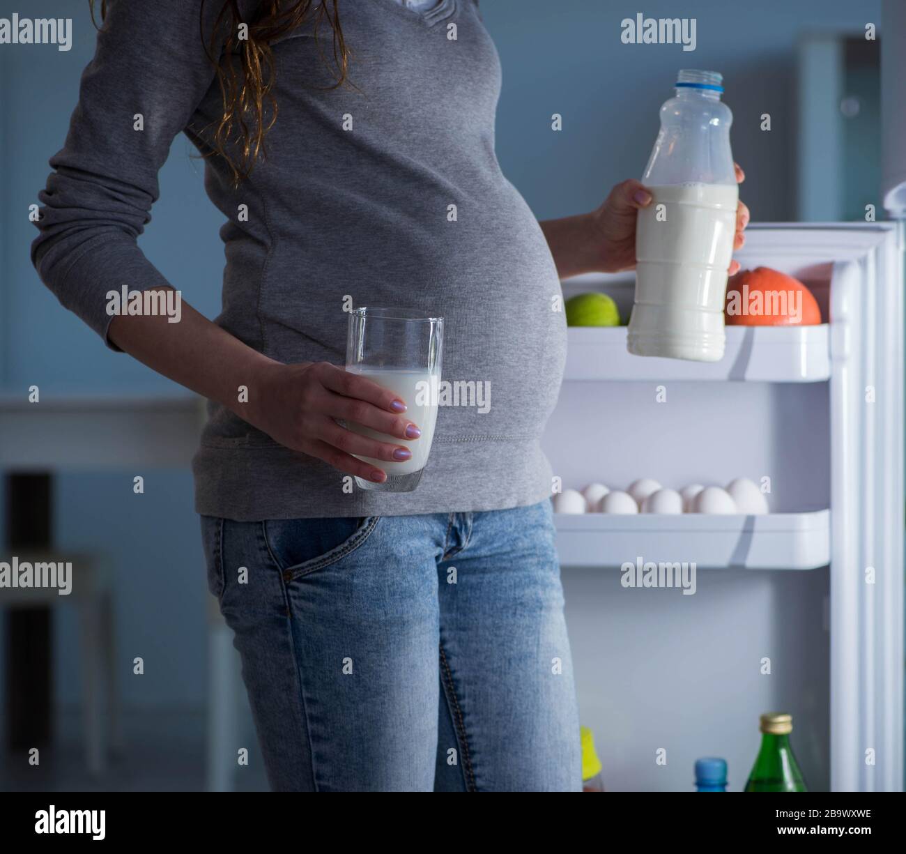 The pregnant woman near fridge looking for food and snacks at night Stock Photo