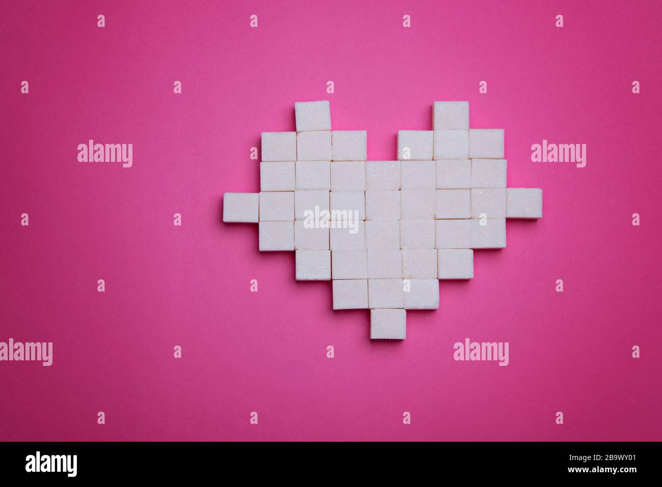 Sugar cubes in the shape of a heart on a bright pink background Stock